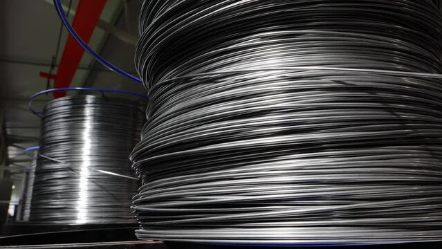 The process of slow unwinding of a metal wire used for a production of metal baskets in an industrial hall.