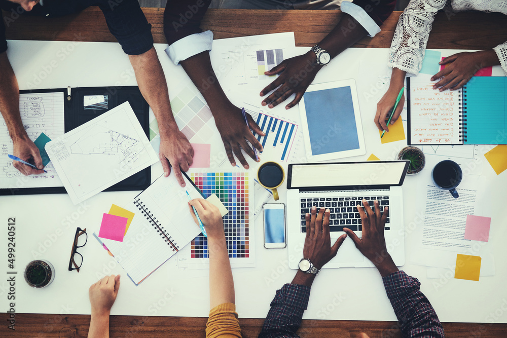 Poster all hands in for a new creative project. high angle shot of a group of businesspeople having a meeti