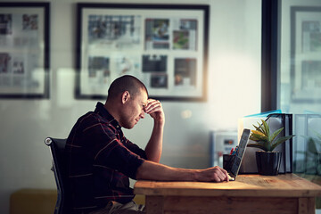 Feeling the pressure. Shot of a tired and stressed businessman working on his laptop while closing his eyes and contemplating.