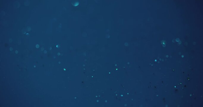 Bokeh glow overlay. Underwater sparkles. Sea bubbles. Defocused blue color shiny round flecks light motion on dark abstract background shot on RED Cinema camera.