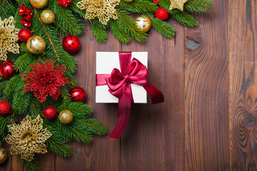 Happy New Year 2023 greeting card. Gift box with red ribbon on wooden background and layout of Christmas tree, balls, gifts. Close up and copy space, Selective focus..