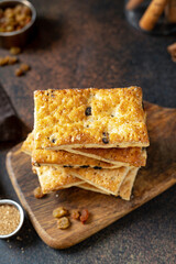 Layered dessert with raisins on the serving board on a dark culinary background. Delicious homemade sweet puff pastry closeup