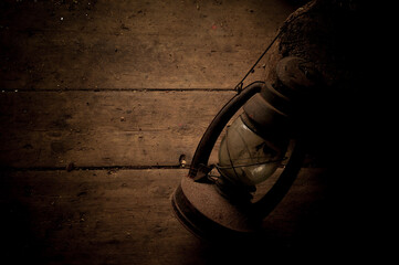 Fototapeta na wymiar Amazing vintage kerosene lamp on a shabby wooden floor. Extremely dark background, brown color
