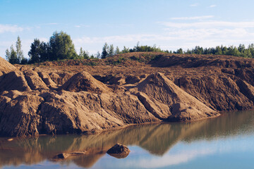 Flooded sand quarry. Cracked drought clay piles during the dry season. Bright yellow or orange...