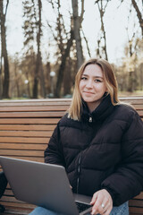 Smiling woman studying on laptop at park