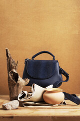 Still life with a blue women's handbag and objects made of natural materials. Eco leather handbag and objects on a wooden background.
