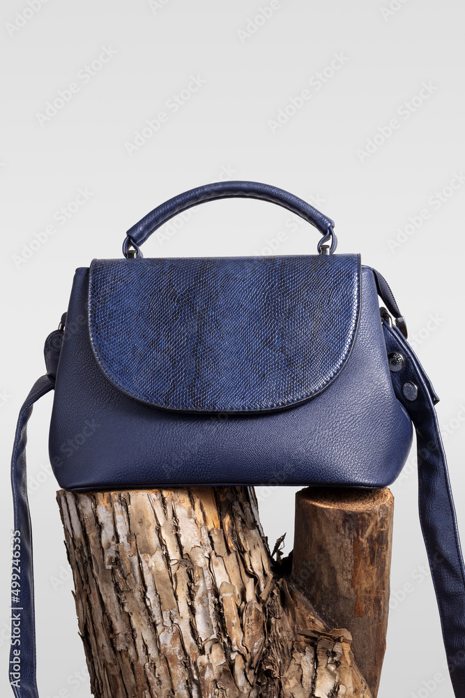 Wall mural blue leather handbag on wooden snag. creative fashion minimal background.