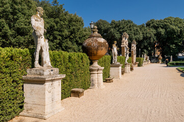 Fototapeta na wymiar Galleria Villa Borghese, detail of the garden of the noble casino, with the classic statues in the park of the villa on a day with blue sky. Center of Rome, Italy.