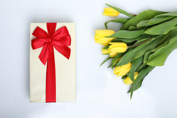 gift box with flower, Spring composition. Delicate yellow tulips and gift on white background top view space for text border. bouquet of fresh yellow tulips on white background 
