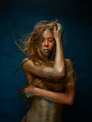 Portrait of naked long-hair blond girl with body art painting on her body