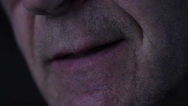 Close up of male mouth mumbling in the dark. 
