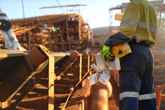 Safe work practises miner wearing work uniform safety glove holding hard hat danger personal safety locks preparing to locking on isolation convertor belt prior working on site