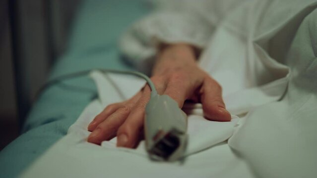 Pulse oximeter patient finger in ward closeup. Hospital emergency care unit.