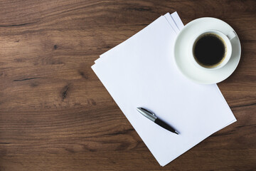 office desk with white sheets, pen and glasses.
