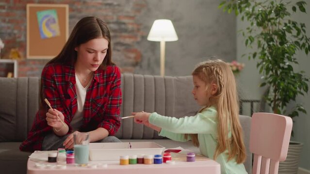 Sister looks teaches sad girl dripping paint for Ebru art
