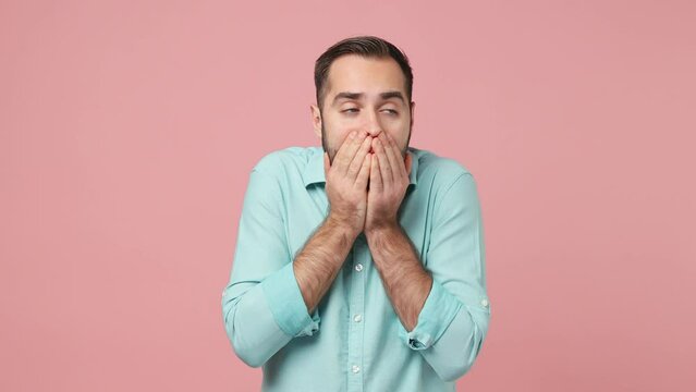 Scared shocked frightened young brunet man 20s years old wears blue shirt look around covering hiding face with hands isolated on plain plain pink background studio. People emotions lifestyle concept
