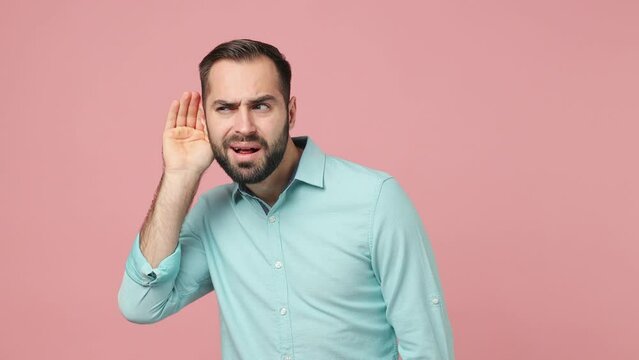 Curious nosy fun young brunet man 20s years old wears blue shirt try to hear you overhear listening intently hot news isolated on plain plain pink background studio. People emotions lifestyle concept