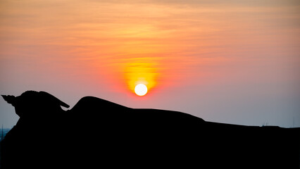 Silhouette reclining buddha on sunset background.
