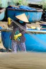 A woman is collecting fish from a fishing net on Phuoc Hai beach, Ba Ria Vung Tau province