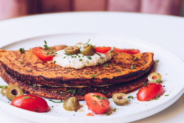 Close up of vegan omelette, with humus, olives and tomatoes.