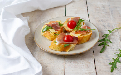 Toast with serrano ham (jamon, prosciutto crudo, hamon), traditional Italian antipasti. Delicious snack with bread, cream cheese, olives. Health food, appetizer for wine, bruschetta