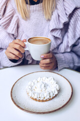 Woman enjoying her coffee and her lemon cheesecake in a cafe.