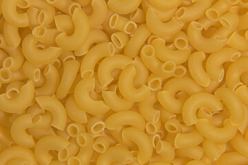 Dry raw yellow pasta. Close-up. Completely background.