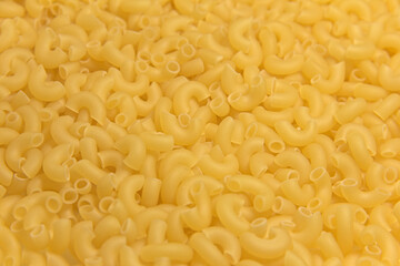 Dry raw yellow pasta. Close-up. Completely background.