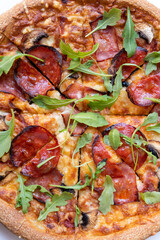 Close up salami pizza with mushrooms and arugula leaves.