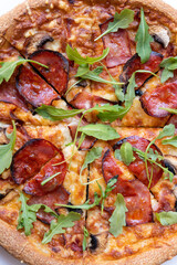 Close up salami pizza with mushrooms and arugula leaves.