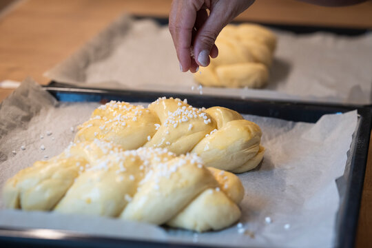 woman's hand sprinkles easter braid with granulated sugar as a decoration for handmade baked goods