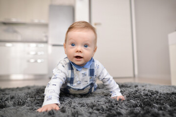 Portrait of a crawling baby on the carpet in home. Smiling crawling baby at home on carpet. 