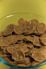 Flakes in a glass plate. On a yellow background. Vertical.