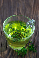 Thyme (thymus vulgaris) herbal tea viewed from above in a glass cup.