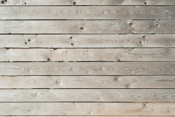 Naklejka premium Wooden fence made of raw rough wood outdoors. Textured horizontal gray planks