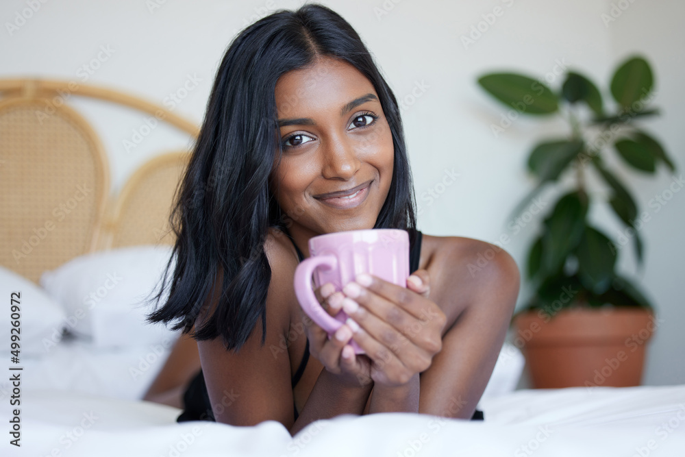 Sticker Its just me and my favourite beverage. Shot of a beautiful young woman holding a cup while lying on her bed.