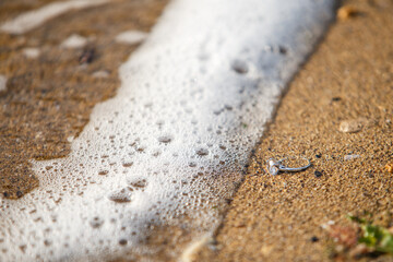 Engagement ring on a beach sand beside a sea wave