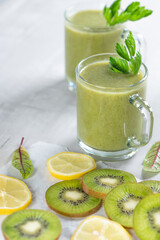 Healthy fresh fruit smoothie drink surrounded by kiwi lime and lemon on a gray concrete background. The concept of a healthy lifestyle and proper nutrition. Vitamin drink.