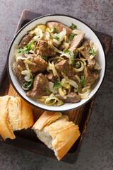 Close-up fried beef liver with onions served in a plate on a wooden tray. vertical top view from above