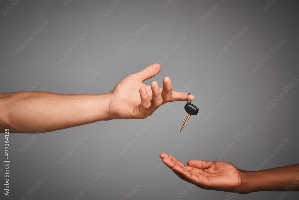 Poster Handing over keys to the designated driver. Studio shot of unidentifiable hands exchanging keys against a gray background.