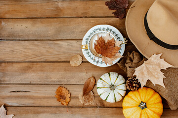 Autumn fall composition. Wooden desk table with knitted sweater, hat and pumpkin. Flat lay, top view. Nordic, hygge, cozy home concept