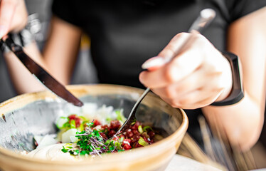 woman hand eating beef tartare using knife and fork fom bowl
