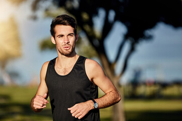 Just keep moving forward. Shot of a young man out for a jog in a park.