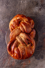 wicker bun made of wheat flour lies on a round wooden board, close-up