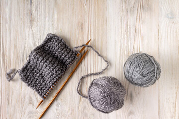Fototapeta premium knitted fabric on wooden knitting needles and balls of yarn on a white wooden background