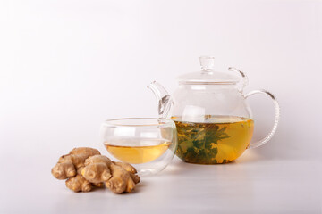 glass teapot with green tea, cup, ginger on a white background