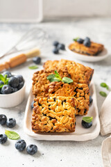 Shortbread bar cookies with blueberries on a serving plate on a light gray kitchen table. Delicious homemade sweet pastries	