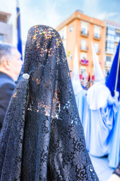 Detail of the head of a woman with a black spanish mantilla and peineta (ornamental comb), seen from behind, in a Holy Week procession