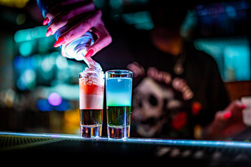 bartender hand making collection of colorful shots. two cocktails at the bar counter