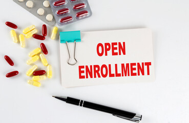 OPEN ENROLLMENT text written in a card with pills. Medical concept.